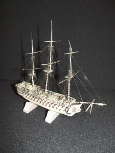 This model of a Man o’ War has been crafted from animal bone by a Napoleonic prisoner of war.  The prisoners made objects from bone, straw and wood which were easy to find, in order to produce high quality objects such as woven straw boxes and models of ships and guillotines. “Man o’ War” was a Royal Navy term from the age of sail for a powerful warship which had many cannons.  This model represents one of the largest of these with 104 guns on three decks, although it is not modelled on any particular ship. The model was very badly damaged; the masts had broken and had detached from the model, and much of the rigging was broken and tangled.  The masts have been put back into position using a two-part adhesive, and the rigging has been repaired and replaced, but only where it has been possible to identify where the original rigging would have been. 