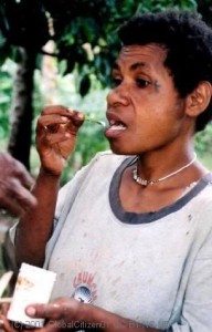 Woman using betel flower to scoop lime, PNG. 
