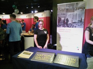 Woman standing at indoor stall promoting Hatton Gallery