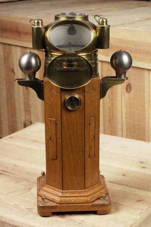Model of a binnacle compass with polished wood body, grey soft iron adjusting balls either side and brass compass chamber above. Made by James Morton and on display in Sunderland Museum