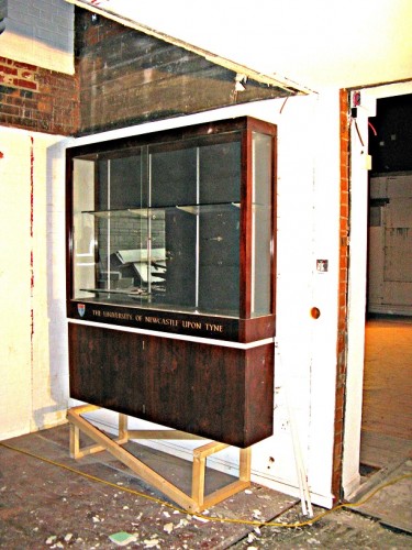 Large wooden and glass display cabinet on wall of building site interior
