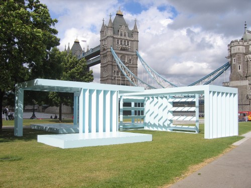 External photo of large light-blue abstract structure sitting on grassed areas with London Twoer Bridge in backcround