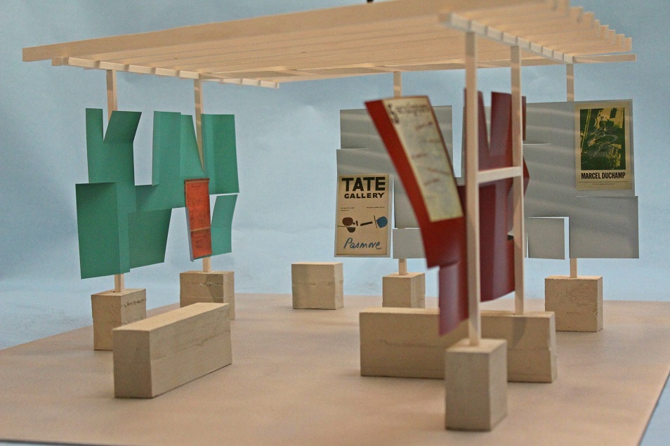 Model open structure with blocksand vertical uprights supporting a roof of crossbeams against blue background - also displaying several small posters within model