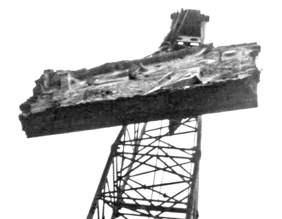 Black and white old photo of large abstract wall sculpture being hoisted into the sky by a large crane