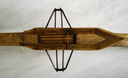 Cockpit of a model of a fixed seat skiff (single scull) c. 1860. The seat is the long flat board that was required to use a sliding stroke on a fixed seat, although the footboard is missing. The frame which once held the footboard in position probably came adrift at the same time. Sadly, it appears that somebody has since glued this frame across the cockpit in a position that would have prevented the full-sized boat from being sculled! TWCMS : B9758 Scale 1:12